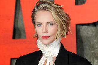 Charlize Theron wearing dark black cherry nails with a subtle blue micro-French tip at a red carpet event