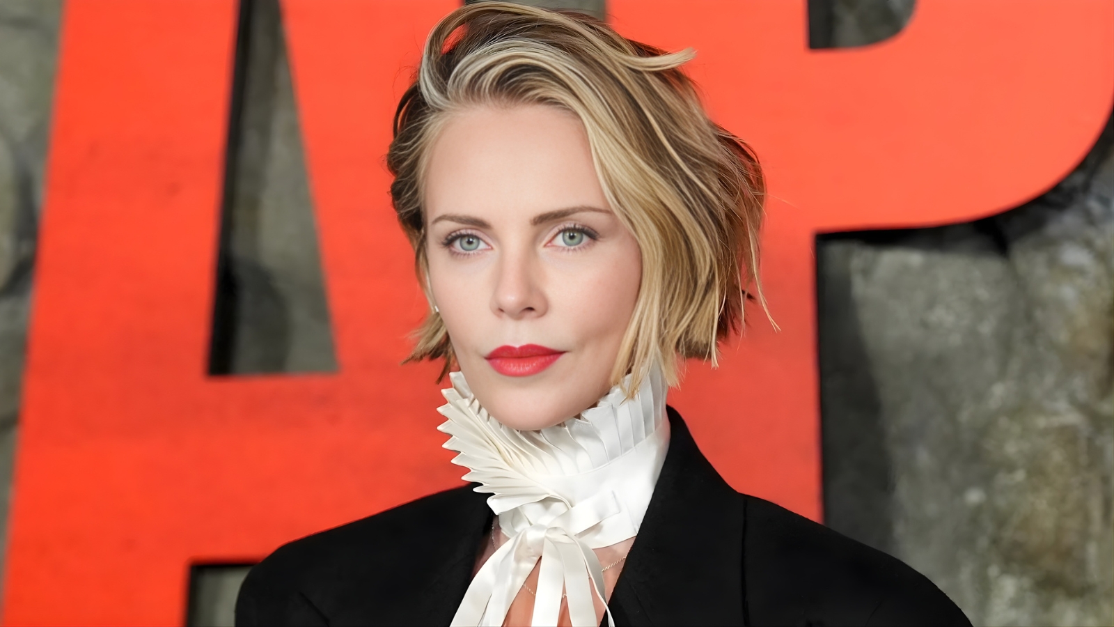 Charlize Theron wearing dark black cherry nails with a subtle blue micro-French tip at a red carpet event