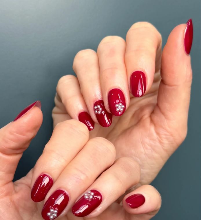 Emily Blunt red carpet French tip manicure with glossy red polish and pearl floral nail art design
