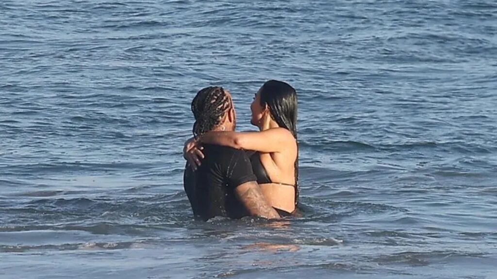 Kim Kardashian and Lewis Hamilton kissing in the ocean during a Malibu beach day, wearing swimwear and enjoying a romantic moment