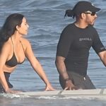 Kim Kardashian and Lewis Hamilton kissing in the ocean during a Malibu beach day, wearing swimwear and enjoying a romantic moment