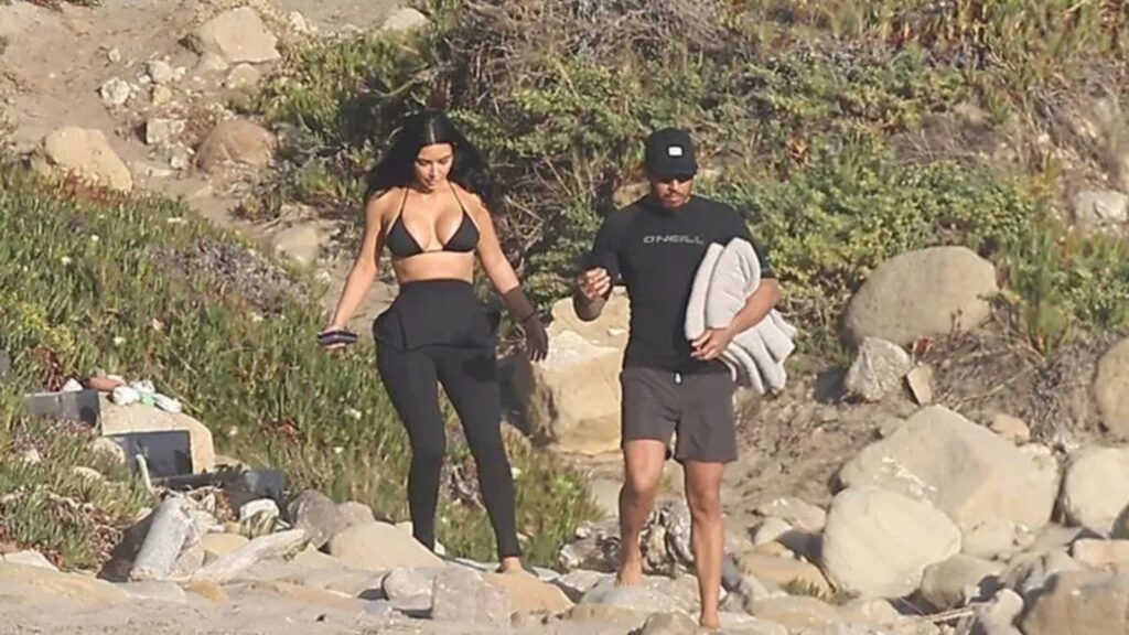 Kim Kardashian and Lewis Hamilton kissing in the ocean during a Malibu beach day, wearing swimwear and enjoying a romantic moment