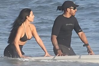 Kim Kardashian and Lewis Hamilton kissing in the ocean during a Malibu beach day, wearing swimwear and enjoying a romantic moment
