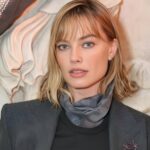 Margot Robbie wearing a charcoal gray Giorgio Armani suit with brooch at Milan Design Week sciura style look