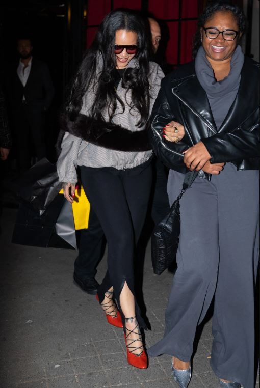 Rihanna leaving César Restaurant in Paris at sunrise wearing a sporty gray checked bomber jacket, Balenciaga leggings, red pumps, and yellow mini handbag