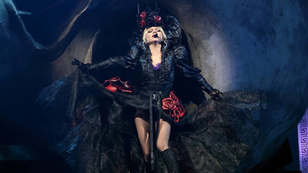 Lady Gaga performing live on stage during her Mayhem Tour with dramatic lighting and a high-energy crowd