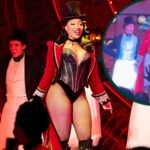 Megan Thee Stallion pausing on stage during a Moulin Rouge Broadway performance, appearing emotional and holding back tears after her breakup news