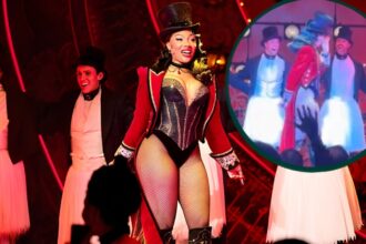 Megan Thee Stallion pausing on stage during a Moulin Rouge Broadway performance, appearing emotional and holding back tears after her breakup news