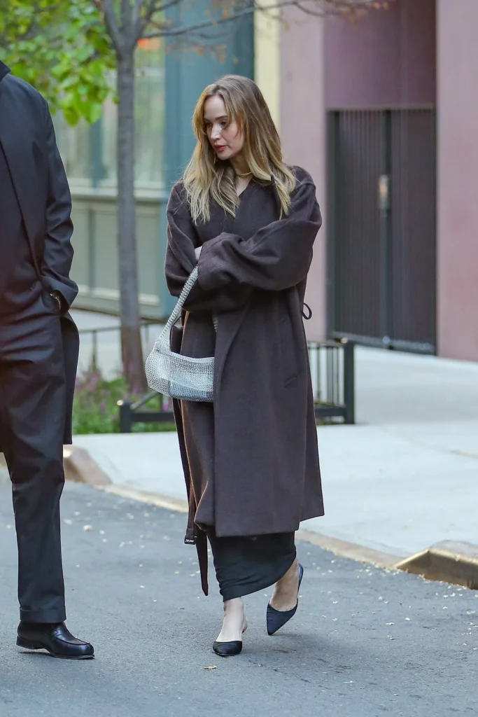 Jennifer Lawrence wearing a black dress and brown coat, carrying a silver see-through statement shoulder bag on a night out