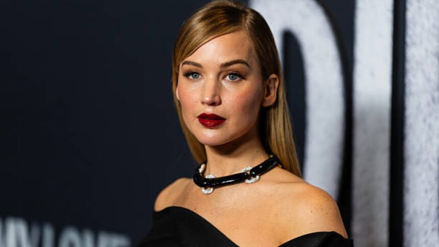 Jennifer Lawrence wearing a black dress and brown coat, carrying a silver see-through statement shoulder bag on a night out