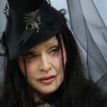 Madonna at the 2026 Met Gala wearing a brunette couture wig with textured waves, top hat, and veil inspired by Ray of Light era