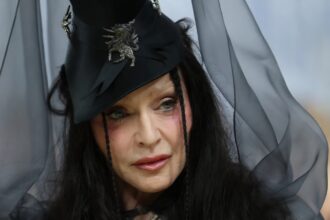Madonna at the 2026 Met Gala wearing a brunette couture wig with textured waves, top hat, and veil inspired by Ray of Light era