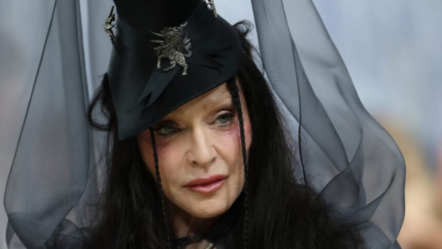 Madonna at the 2026 Met Gala wearing a brunette couture wig with textured waves, top hat, and veil inspired by Ray of Light era