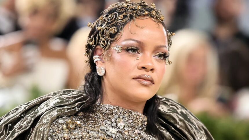 Rihanna at the 2026 Met Gala wearing a metallic Maison Margiela gown with gold makeup, glowing skin, glossy lips, and face gems