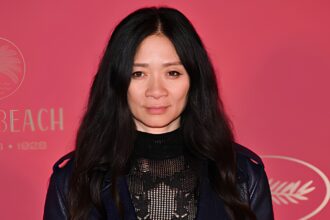 Director Chloé Zhao wearing an elegant black lace and knit dress with a leather moto jacket at the Cannes Film Festival red carpet.