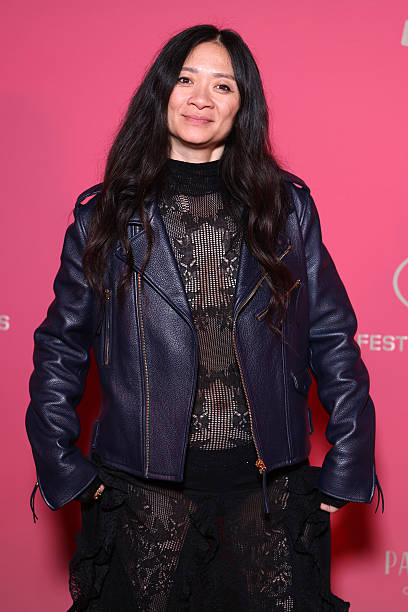 Director Chloé Zhao wearing an elegant black lace and knit dress with a leather moto jacket at the Cannes Film Festival red carpet.