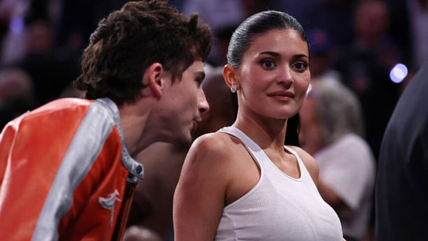Kylie Jenner and Timothée Chalamet kissing courtside at a New York Knicks game at Madison Square Garden while wearing matching orange jackets and jeans