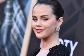 Selena Gomez wearing a sleek bun and classic bright red nail polish at the Los Angeles premiere of Marty, Life Is Short in a black beaded Carolina Herrera dress